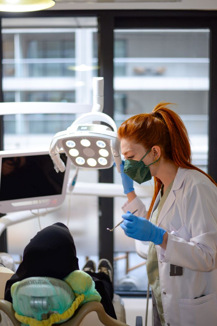 A female dentist conducts a dental checkup in a modern clinic, wearing surgical gloves and a mask.