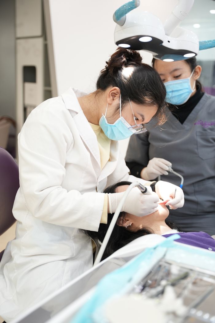 Two dentists performing a dental procedure on a patient in a modern clinic setting.