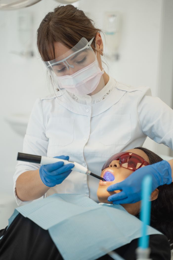 Dentist using dental curing light on patient in clinic setting. Health and care focus.