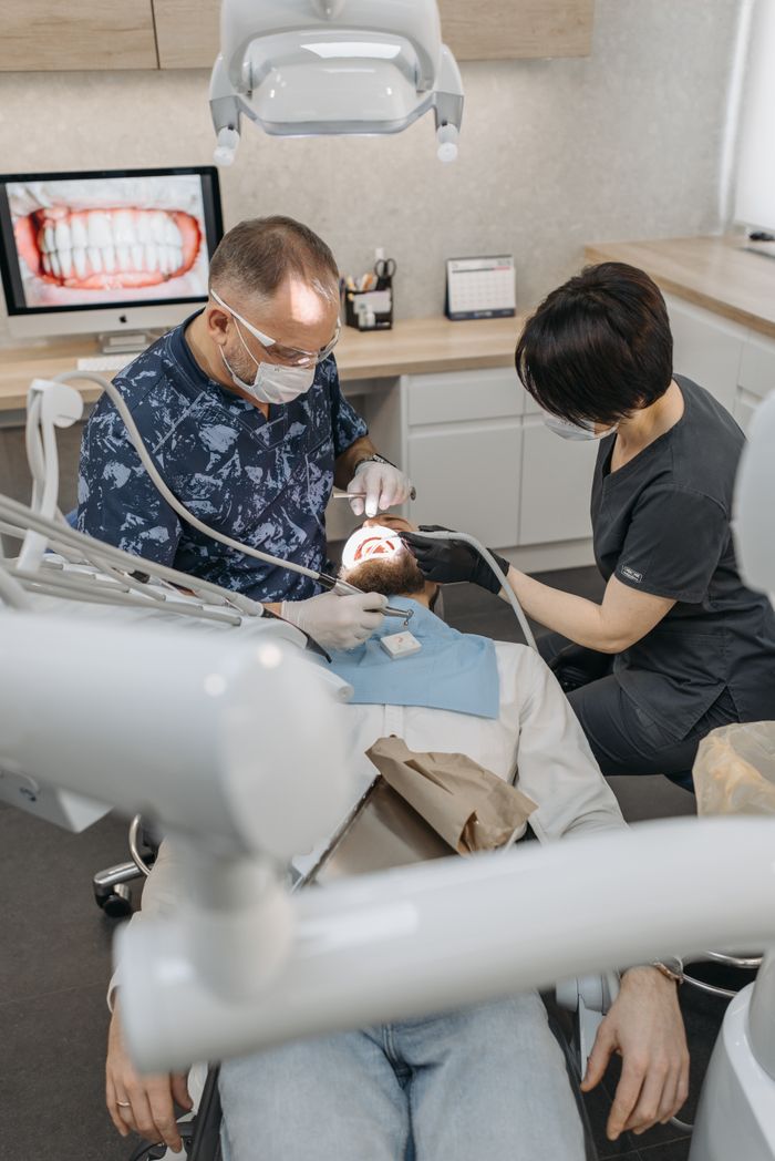 Dentist and assistant performing a dental procedure in a clinic with modern equipment.