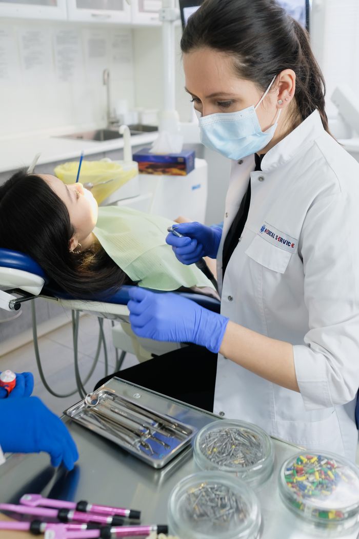 Dentist in face mask attending to a patient's oral hygiene in a modern clinic setting.